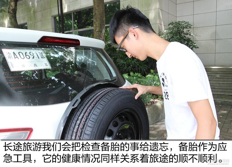 车辆停在平坦路面，千斤顶支撑在底盘指定位置，车主正在用扳手按对角线顺序拧紧备胎螺丝，旁边放着旧轮胎和工具包