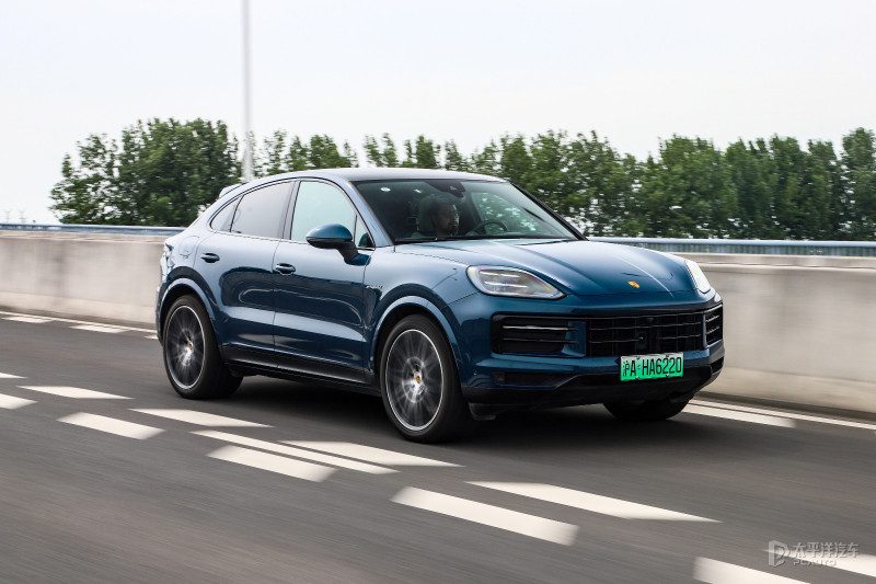 保时捷Cayenne Coupé E-Hybrid在都市街头静态展示，背景是现代化建筑，强调溜背造型与流畅线条